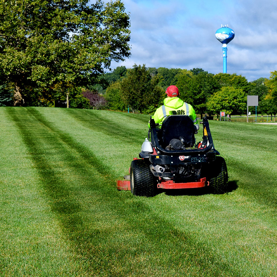 DJ's Landscape Management employee riding a mower providing commercial landscape maintenance services