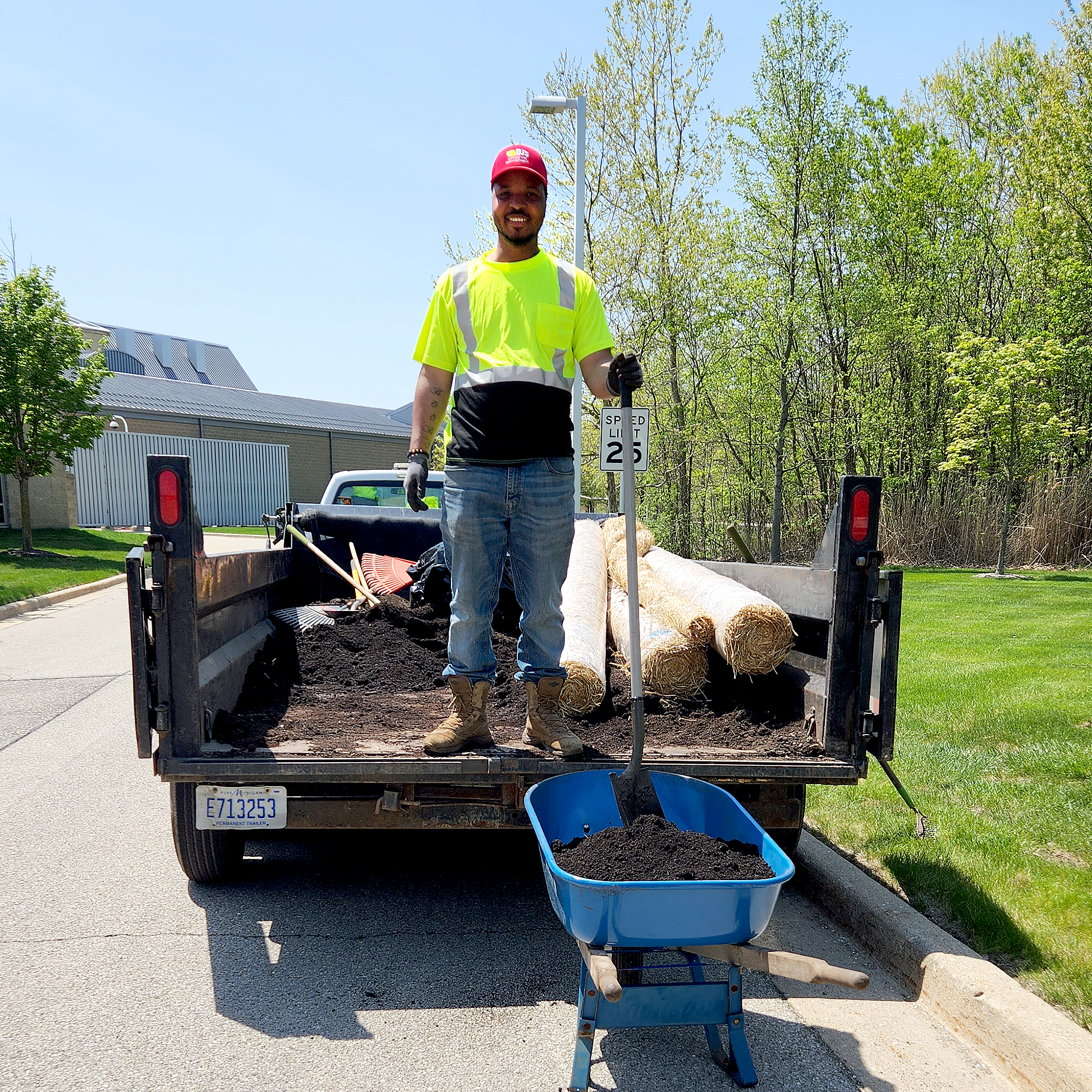 DJ's Landscape Management employee standing in the bed of a truck filled with soil