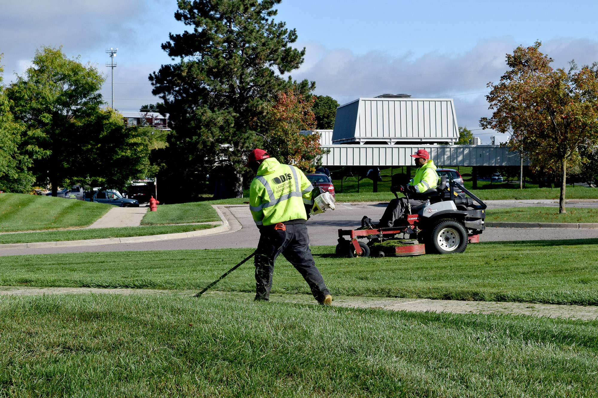 two DJ's Landscape Management employees wearing bright yellow hoodies providing landscaping services at a commercial property