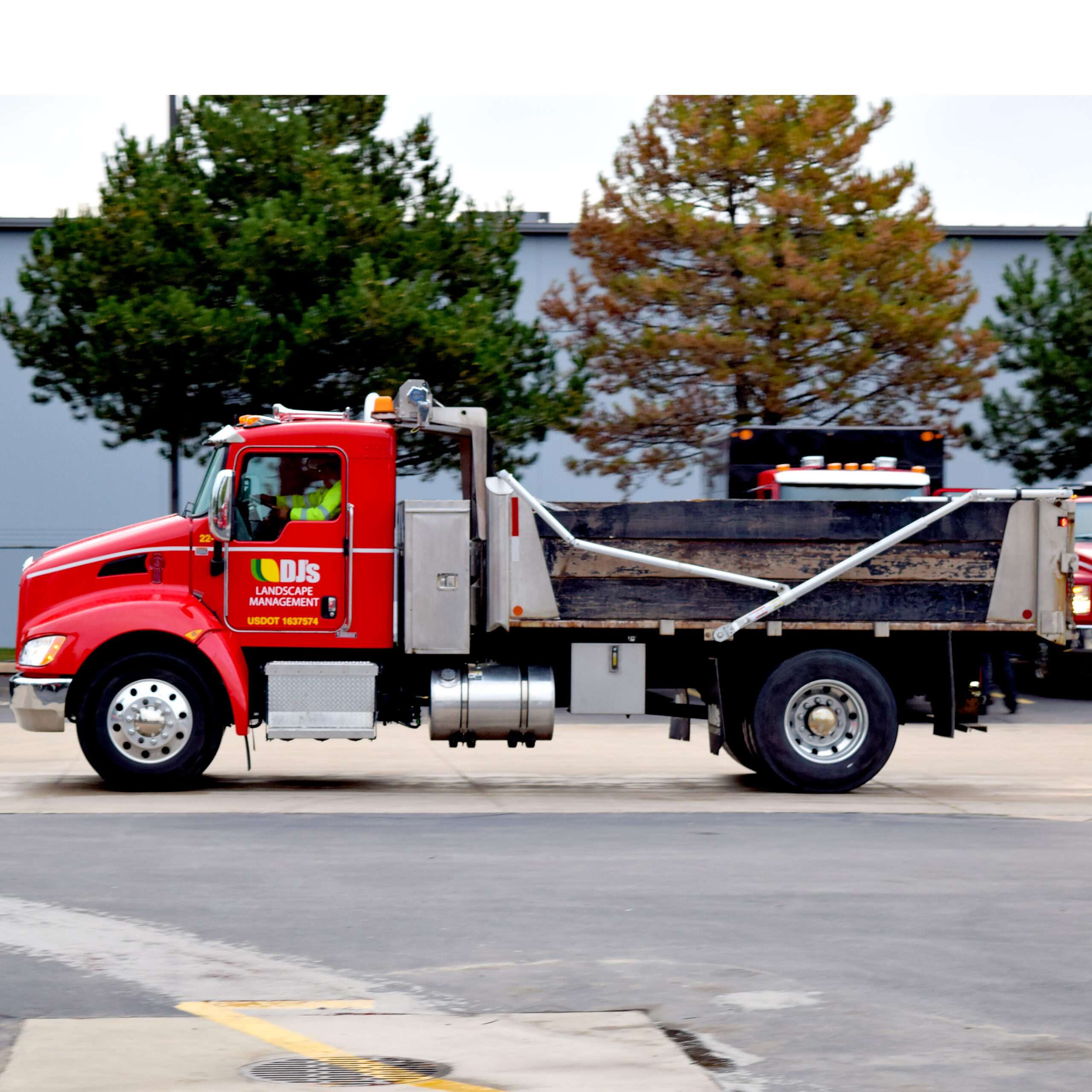 DJ's Landscape Management employee driving a red company truck in a parking lot